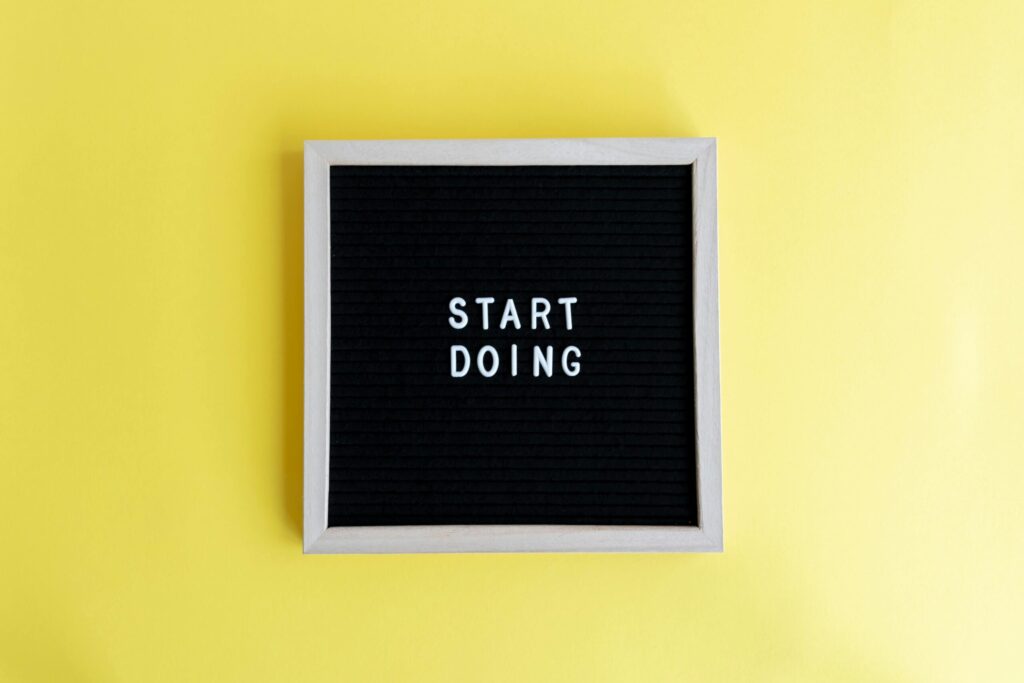 Black message board with 'Start Doing' on a bright yellow background for inspiration.
