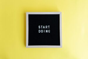 Black message board with 'Start Doing' on a bright yellow background for inspiration.