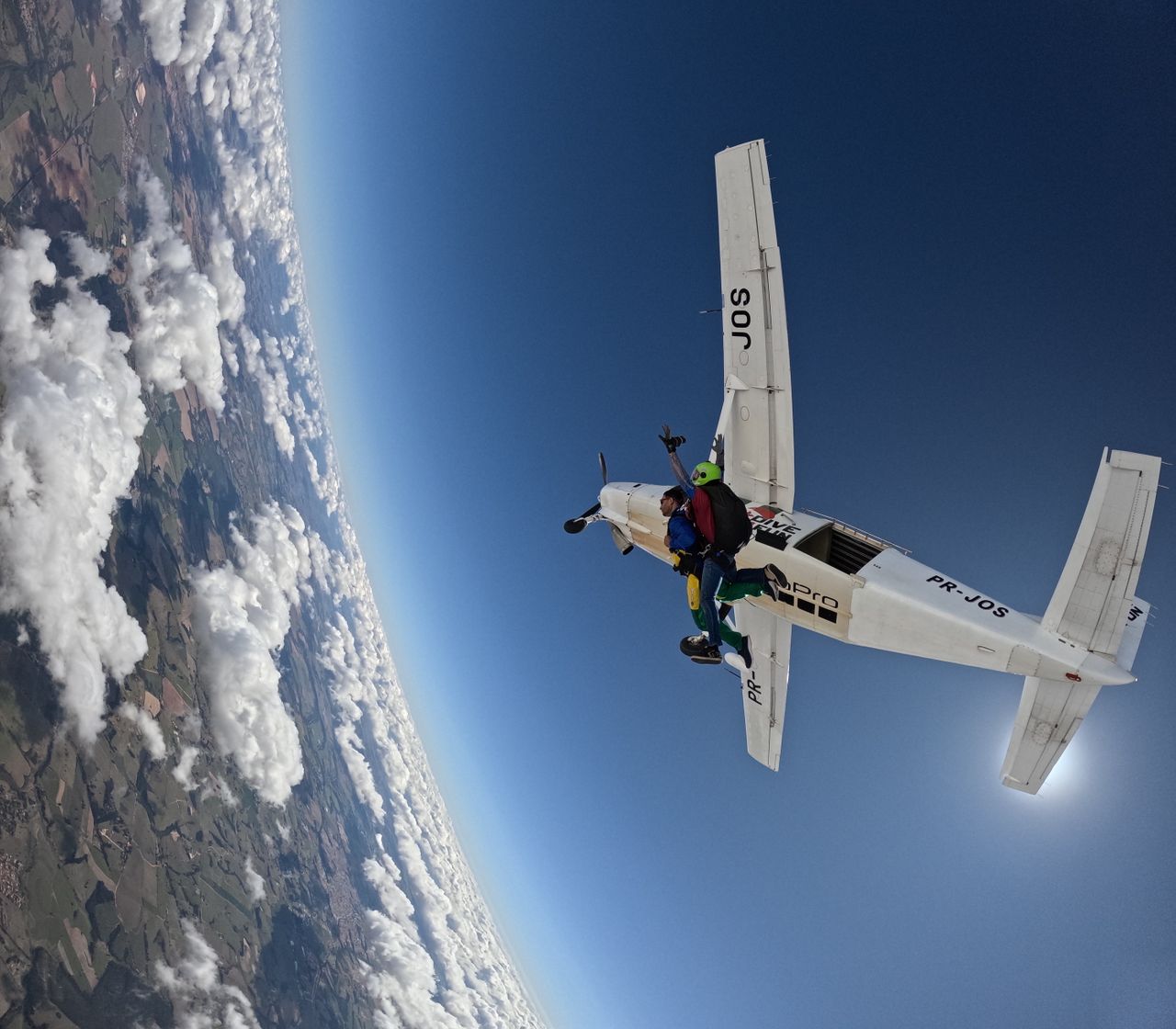 Exciting tandem skydiving jump from aircraft, high above scenic landscape.